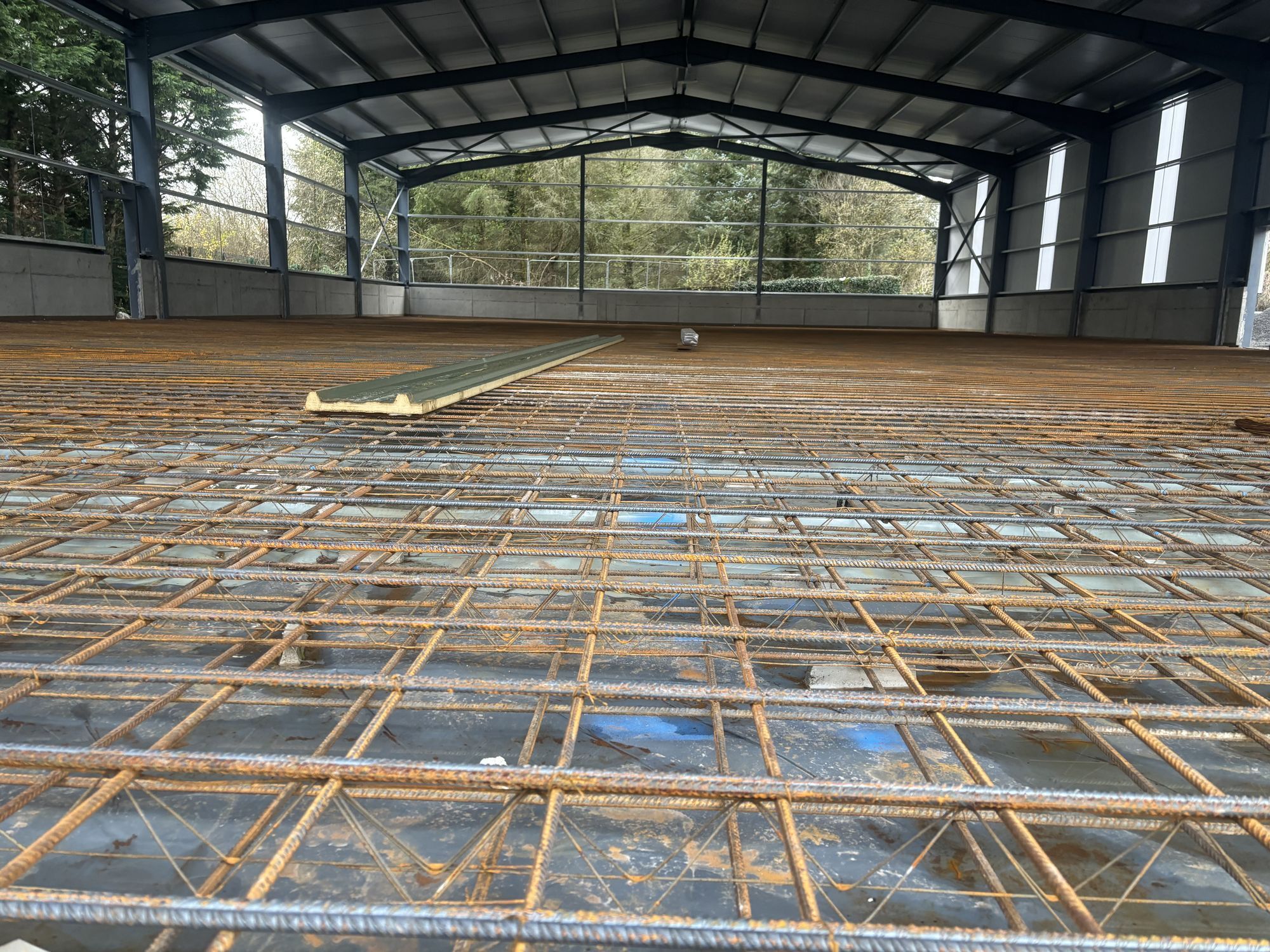Reinforcement mesh laid across the floor of a large steel-framed shed